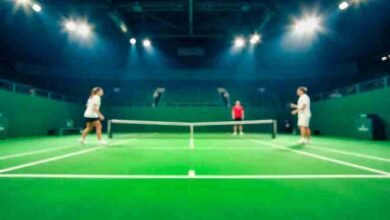Tennis players competing on a bright green court under modern stadium lights.