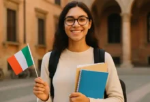 Male international student standing outside a historic Italian university building, holding study documents and smiling.