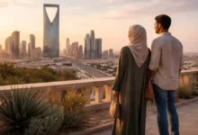 Riyadh skyline at golden hour with Kingdom Centre Tower as a couple looks out from a terrace viewpoint in Saudi Arabia.