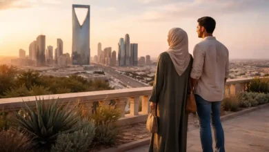 Riyadh skyline at golden hour with Kingdom Centre Tower as a couple looks out from a terrace viewpoint in Saudi Arabia.