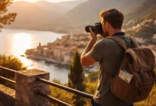 Travel photographer taking a photo at golden hour overlooking a coastal town and mountains for stunning travel photography.