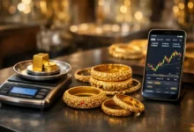 24K gold jewelry and coins on a digital scale with a smartphone showing a gold price chart in a Pakistan sarafa market