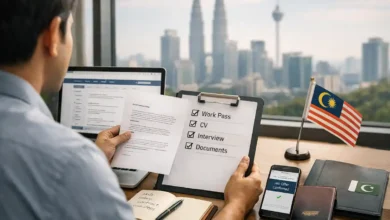 Pakistani professional reviewing a Malaysia job offer with work pass, CV, interview and documents checklist in Kuala Lumpur office